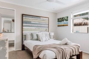 a white bedroom with a large bed with a blanket on it at Entertainment Haven 900m to the Beach in Kawana Waters