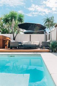 a swimming pool with chairs and an umbrella at Entertainment Haven 900m to the Beach in Kawana Waters