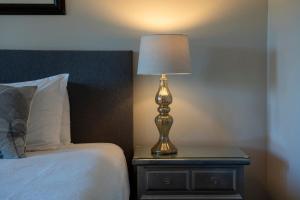 een lamp op een nachtkastje naast een bed bij Maple Rise Guesthouse in Duncan