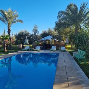 a swimming pool with chairs and a gazebo at Riad les deux citronniers in Marrakesh