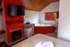 a bathroom with a bed and a tub and a television at Pousada Flores da Serra in Monte Verde