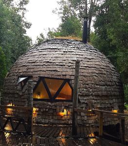 a large stone dome house with a wooden fence at Domo del bosque in Dalcahue