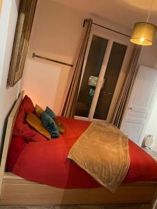 ein rotes Bett in einem Zimmer mit Fenster in der Unterkunft Logement confortable haut de gamme ~ Paris/Vanves in Vanves