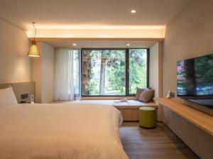 a bedroom with a large bed and a large window at Howard Resort Xitou in Lugu