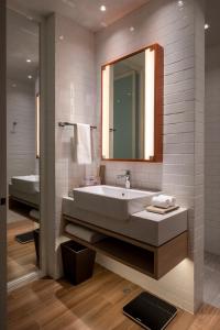 a bathroom with a sink and a mirror and a tub at Brittany Hotel BGC in Manila