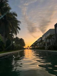 una piscina de agua con palmeras y una puesta de sol en Beach front Blue Summer Apartment Costa Del Sol en El Zapote