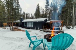 two chairs and a fire in front of a cabin at Awesome family vacation home in Bragg Creek in Bragg Creek