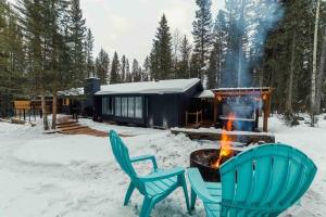 2 chaises et une cheminée devant une cabine dans l'établissement Awesome family vacation home in Bragg Creek, à Bragg Creek