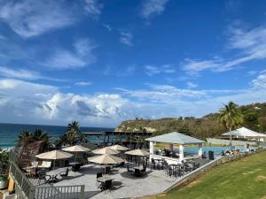 eine Terrasse mit Tischen und Sonnenschirmen am Meer in der Unterkunft Hotel El Guajataca in Quebradillas