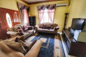 a living room with couches and a flat screen tv at Homestay Jasmin Indah, Senawang (free wifi) in Seremban