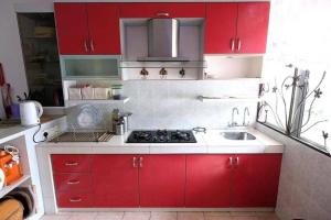 una cocina con armarios rojos y fregadero en Homestay Jasmin Indah, Senawang (free wifi), en Seremban