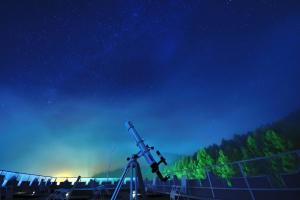 a starry night with a telescope in a field at Ashibetsu Onsen Starlight Hotel in Ashibetsu