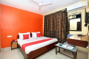 1 dormitorio con 1 cama con pared de color naranja en Hotel Rajmahal, en Jalandhar