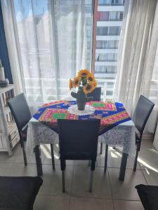 a dining room table with a vase of flowers on it at Hermoso departamento, cómodo y tranquilo, cerca de todo, a pasos de la playa in Iquique