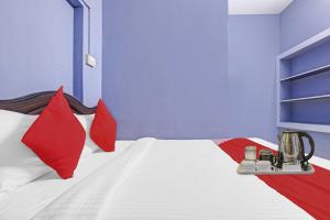 a bedroom with a bed with red pillows at Hotel O Stayz in Auroville