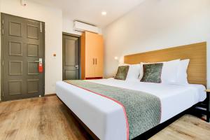 a bedroom with a large white bed and a door at Townhouse Century Hotel in Nagpur
