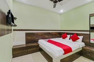a bedroom with a bed with red pillows and a tv at Hotel O Royal in Rāj Nāndgaon