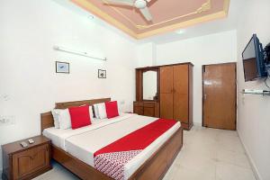 a bedroom with a large bed with red pillows at Hotel Queensland in Amritsar