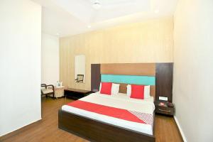 um quarto com uma cama grande e almofadas vermelhas em Hotel Queensland em Amritsar
