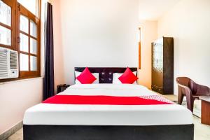 Un dormitorio con una cama grande con almohadas rojas. en Hotel O Royal Inn, en Faridabad