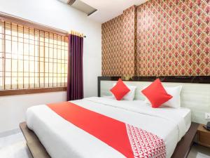 a bedroom with a large bed with red pillows at Flagship Savitri Regency in Bhopal