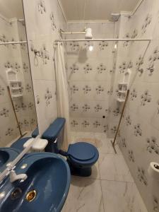 uma casa de banho com um WC azul e um chuveiro em Apart Morel em Puerto Iguazú