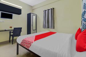 1 dormitorio con 1 cama con manta roja y escritorio en OYO Ruby Grand Inn Nallagandla, en Lingampalli