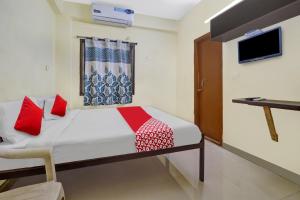 Dormitorio con cama, escritorio y TV en OYO Ruby Grand Inn Nallagandla, en Lingampalli