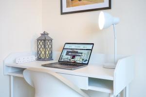 a laptop computer sitting on top of a white desk at Canal View Apartment - City Centre - Free Parking, Balcony, Fast Wifi, SmartTV with Netflix by Yoko Property in Northampton