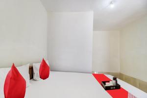 a bedroom with a white bed with red pillows at OYO Grand Royals Anjuna Near Anjuna Beach in Anjuna