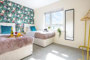 een slaapkamer met 2 bedden en een bloemrijke muur bij Canal View Apartment - City Centre - Free Parking, Balcony, Fast Wifi, SmartTV with Netflix by Yoko Property in Northampton