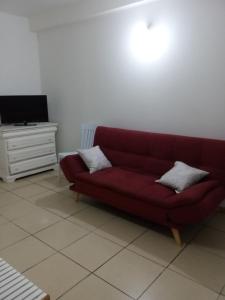 um sofá vermelho sentado numa sala de estar com uma televisão em Relax Time Dumanoir em Capesterre-Belle-Eau