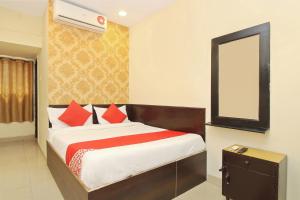 1 dormitorio con cama con almohadas rojas y espejo en OYO Vasundhara Guest House Near Tankbund, en Secunderābād