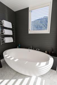 baño con una gran bañera blanca y ventana en Eichardt's Private Hotel, en Queenstown