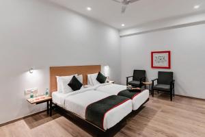 a hotel room with a large bed and two chairs at Super Townhouse 096 Lohia Park in Vibhuti Khand