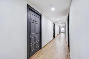 un couloir vide avec une porte noire et du parquet dans l'établissement Townhouse The Royal Retreat, à Garui