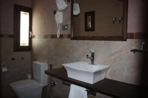 Un baño con lavabo, inodoro y espejo. en Hotel Mesón del Gallo, en Albarracín