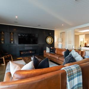 a living room with leather couches and a fireplace at Eichardt's Private Hotel in Queenstown