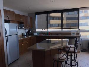 a kitchen with a white refrigerator and two bar stools at Beachfront Calafia Condos in Rosarito