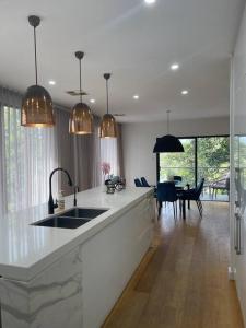 a white kitchen with a sink and a dining room at Unique 3 Bedroom House close to Merewether Beach in Merewether