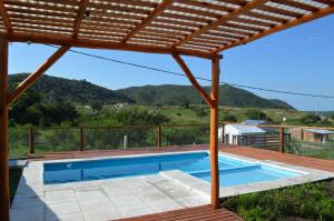 a swimming pool under a wooden pergola at Complejo de Cabañas Valentino in Embalse