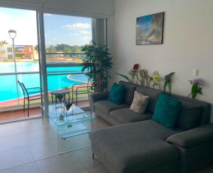 un soggiorno con divano e una piscina di Departamento 'Hozanek' en Dream Lagoons Cancun a Cancún