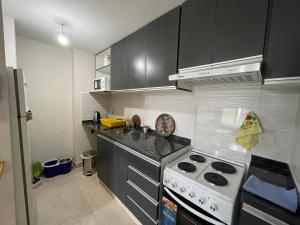a kitchen with black cabinets and a white stove top oven at Monoambiente centrico Plaza Belgrano in San Salvador de Jujuy