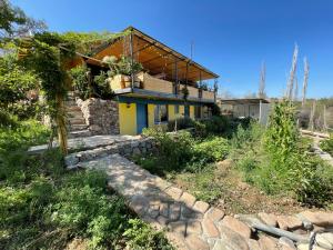 a yellow and blue house with a stone wall at Cabalgatas y Alojamiento LocuraChile in Hurtado