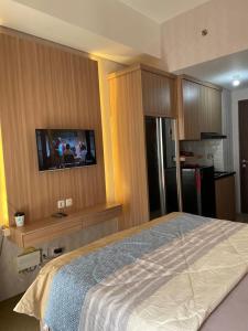 a bedroom with a bed and a tv on the wall at Apartemen Studio View Waterpark in Bulanbulan