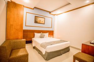 a bedroom with a bed and a chair in it at Lien Do Star Hotel in Bảo Lộc