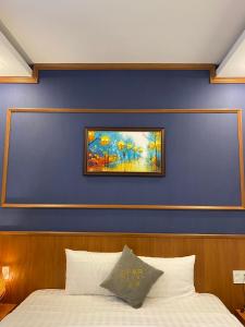 a bed with a blue wall with a painting on it at Lien Do Star Hotel in Bảo Lộc