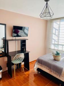 Dormitorio con cama, escritorio y TV en Habitación cerca aeropuerto el Dorado, en Bogotá