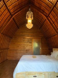 een slaapkamer met een groot bed en een kroonluchter bij Sugita Wooden House in Payangan