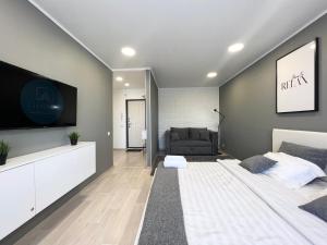 uma sala de estar com uma cama e uma televisão de ecrã plano em Элитная квартира в центре em Pavlodar